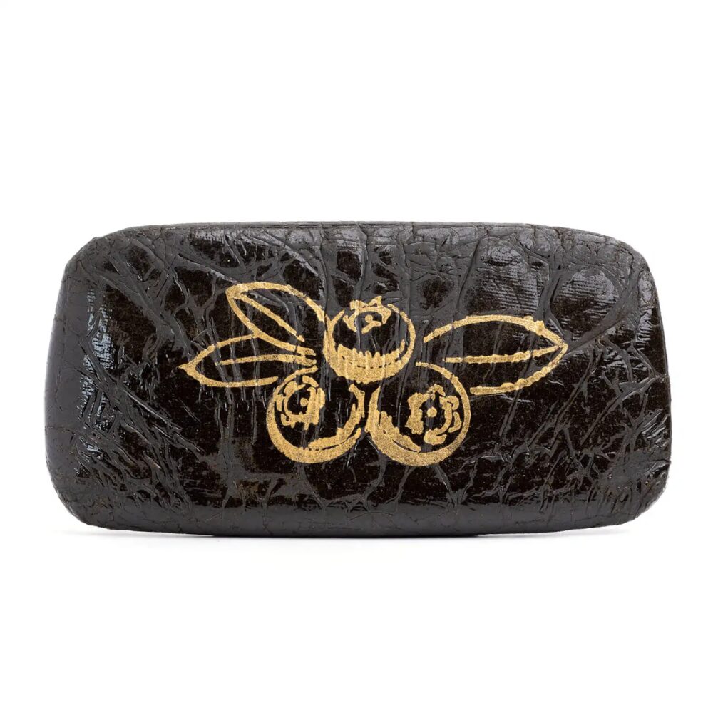 Brick of Blueberry Hash with a stamp of an outline of gold blueberries pressed into the surface, propped up on a clean white background