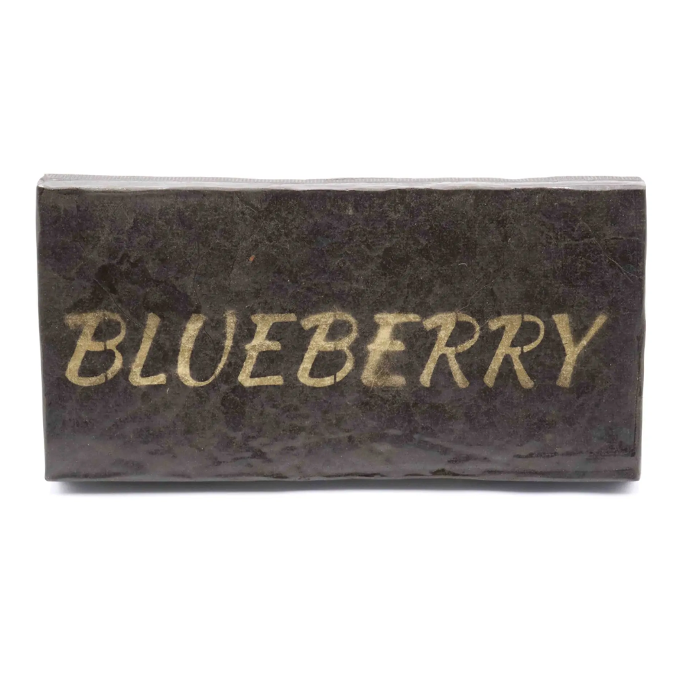 Brick of Blueberry Hash with a "Blueberry" gold stamp pressed into the surface, propped up on a clean white background