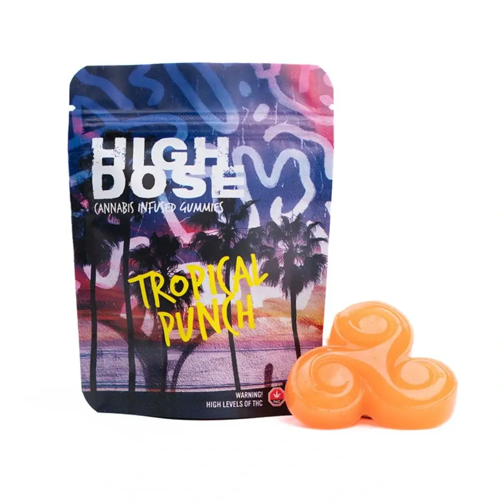 Front packaging of High Dose – Tropical Punch Gummies displayed on a white background with one tropical punch gummy placed beside it.